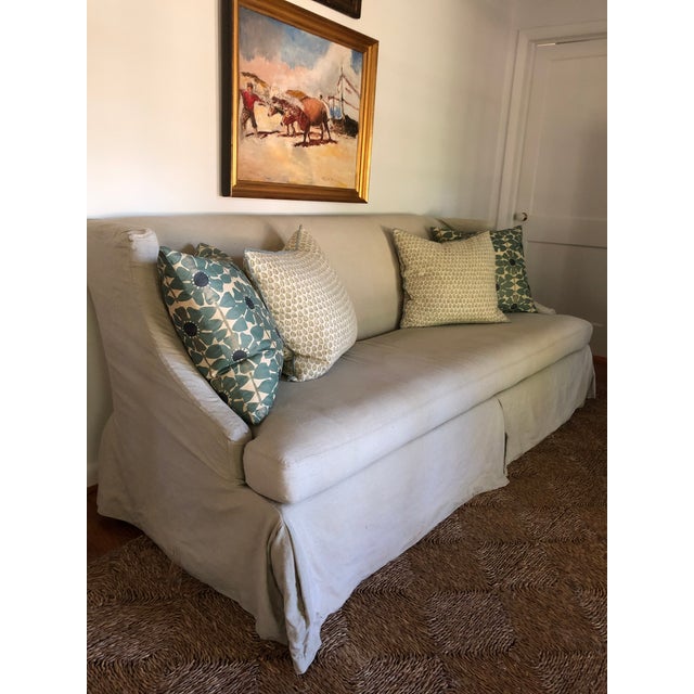 Lee Industries sofa slipcovered in a blue-grey linen. Slipcover skirted with pleats at corners and center. Bench cushion...