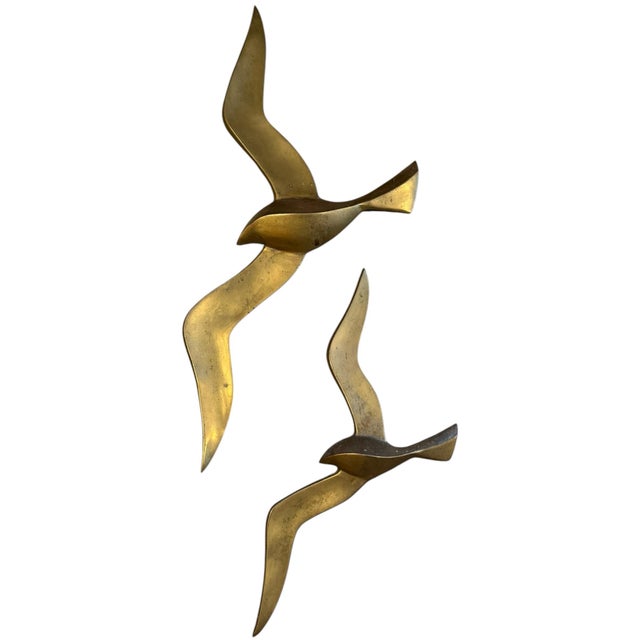 Striking vintage pair of sculptural brass seagulls by Penco, featuring sleek, abstract silhouettes captured in flight. The...