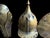 A three-piece brass armor display featuring a pointed helmet, round shield, and matching forearm guard mounted on a dark...