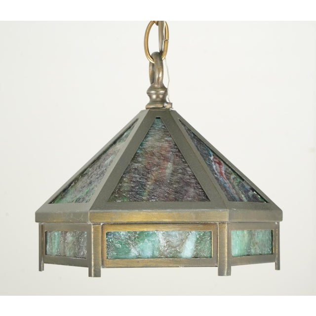 Arts & Crafts style pendant light featuring marbled green slag panels and brass framing. The chain is made of steel. This...