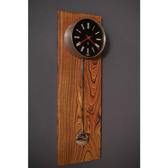 Vintage Pendulum Wall Clock manufactured by Howard Miller, circa 1970's. This stand out piece features stunning zebra wood...