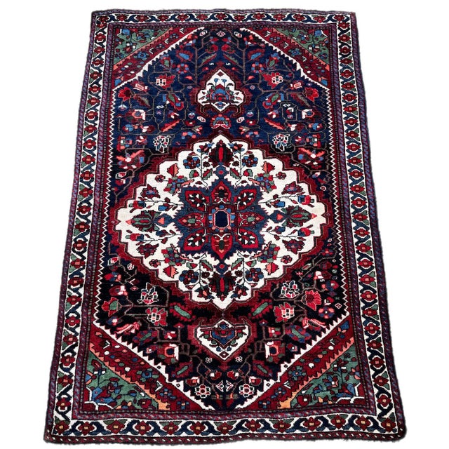 A lovely antique tribal rug, woven by the Lors tribe circa 1900. The design features a single floral medallion on a deep...