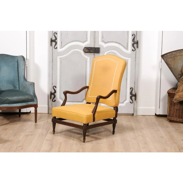 A French walnut Transition period armchair from the 18th century with scrolling arms, fluted tapering legs and carved...