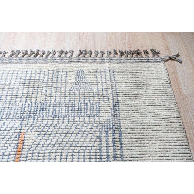 This hand knotted pile rug is crafted from wool and features a primary color palette of ivory, beige, cream, and white....