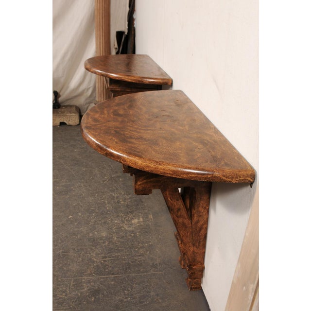 A pair of English wall-mounted demi consoles from 19th century fragments with a faux burl wood finish. These one of a kind...