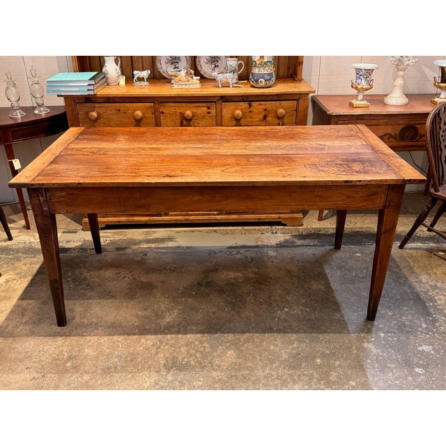A 19th century fruitwood farm table, the plank top raised on square tapering legs joined by pegged mortise and tenon...
