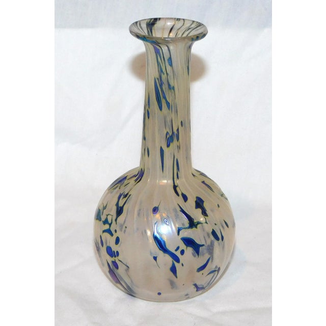 Hand blown glass bud vase in an iridescent white with blue splotches and spiral ribs. Signed, "RHAG" for Robert Held Art...