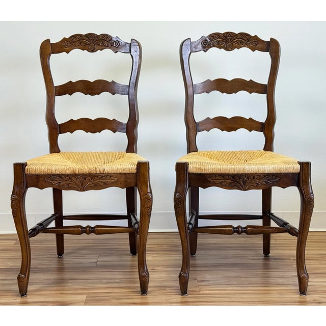 Pair of timeless antique French Country style carved walnut rush seat side chairs. Stunning carved wood floral motif backs...