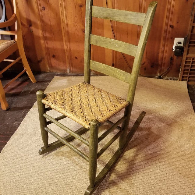 Wood rocking chair with woven seat. In great condition for the age of this piece. Wood is stained or painted an olive...
