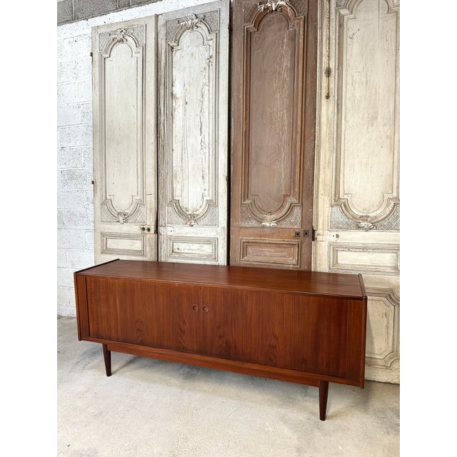 Scandinavian teak sideboard attributed to Svend Aage Larsen, circa 1960. The sliding doors feature handles carved into the...