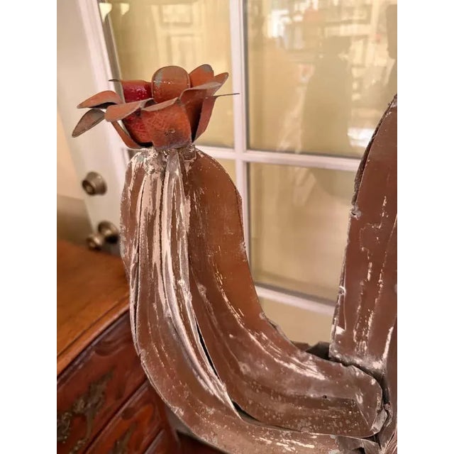 This whimsical garden sculpture takes the form of a stylized cactus, rendered in painted metal with a weathered brown...