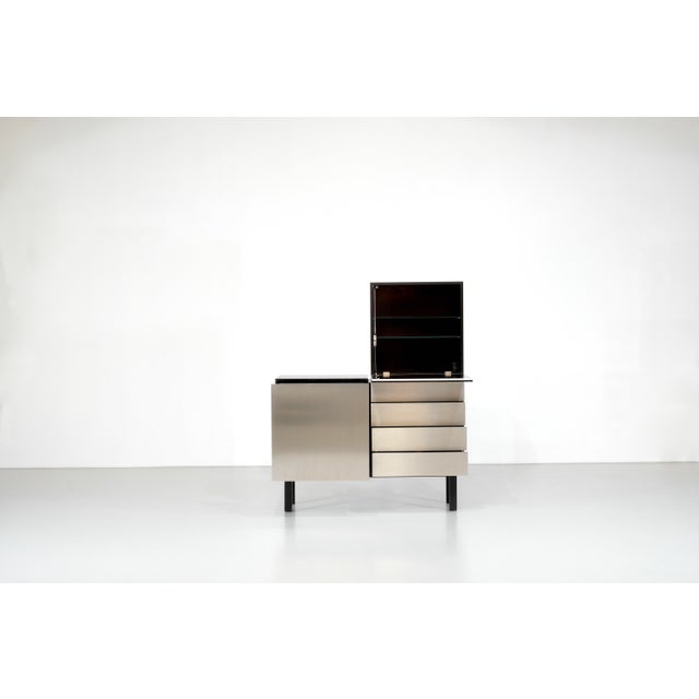 The "Parioli System" sideboard is a tall cabinet made of black-stained ash, accented with satin-finish stainless steel...