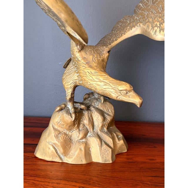 Patinated brass American bald eagle sculpture perched on a rock.