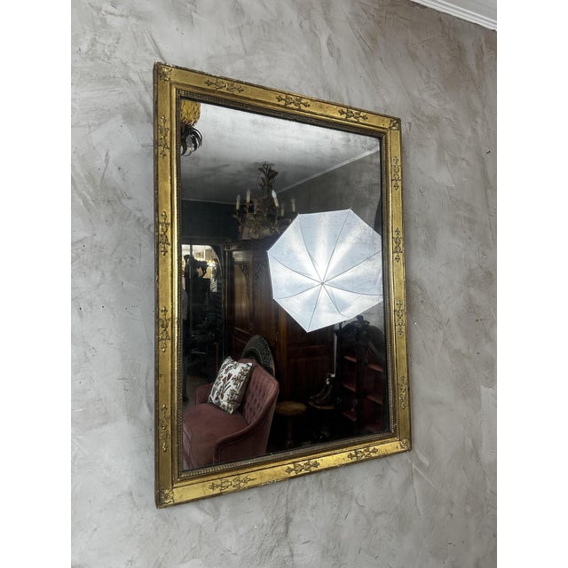 An elegant Empire-style mirror in giltwood, dating from the early 19th century, showcasing the understated yet majestic...