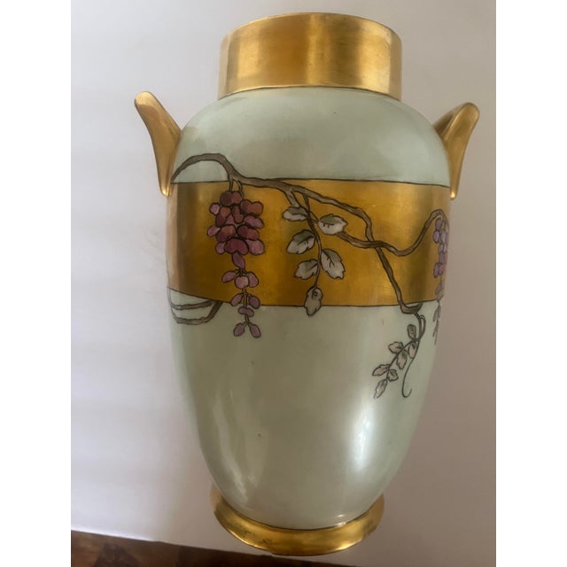 A Limoges porcelain hand painted circa 1920 2-handle vase featuring an Asian child under an umbrella. It is a white...