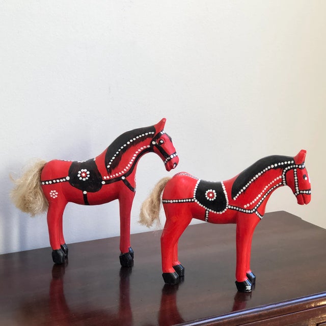 Offering a pair of vintage European carved wood folk art horses with bright red lacquer finish and jute tails. Similar to...