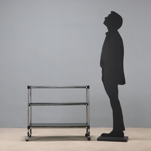 Three-tier service trolley, with an adjustable central tier, in chromed metal and smoked glass. Good condition. This piece...