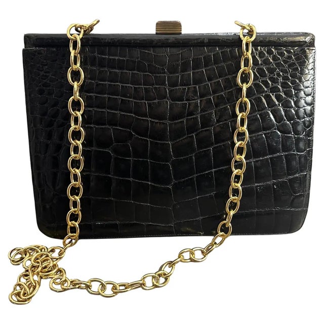 This is an elegant Italian shoulder bag from the 1950s, showcasing a luxurious combination of black leather and brass...