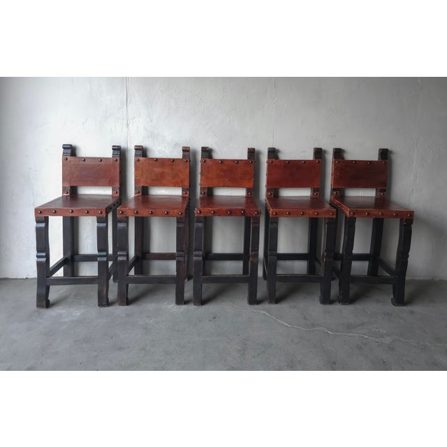 Gorgeous set of 5, mid 20th century, Spanish Colonial Hacienda style barstools. These stools feature beautiful patinated...