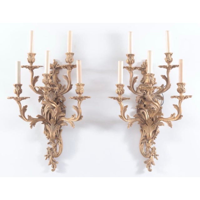 Elegant pair of French Louis XV style five-light ormulu brass wall sconces, finely crafted with an elaborate scrolling...