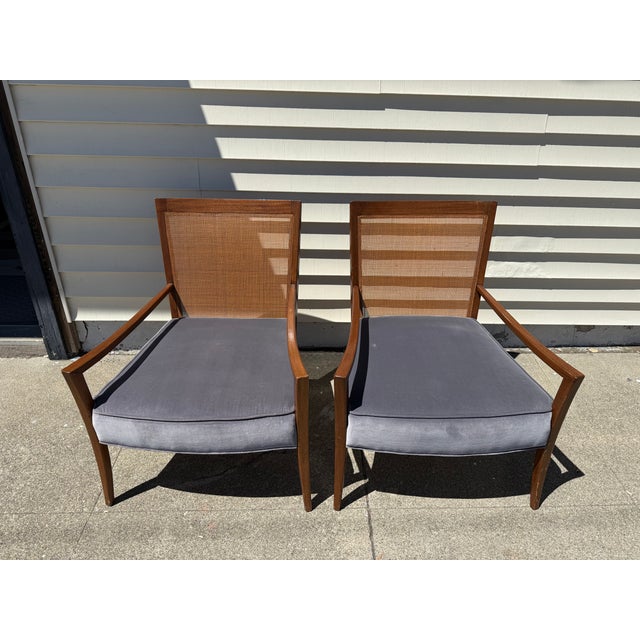 Pair of mid-century modern lounge chairs with sculpted walnut-toned frames, tapered splayed legs, and original caned...