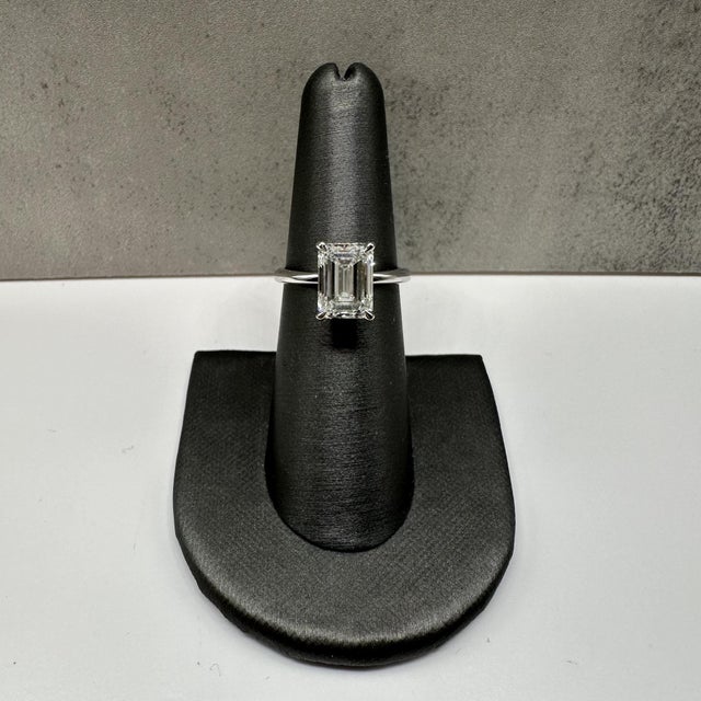 This stunning lab diamond solitaire engagement ring in 14kt white gold features a breathtaking 3.10 carat emerald cut...