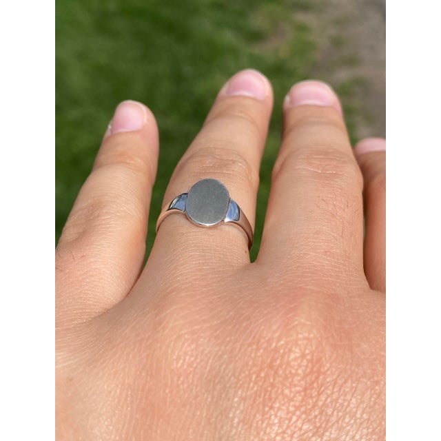 This stunning piece, known as The Classic Signet, features a sleek and timeless design. The oval-shaped signet face is...