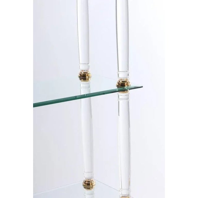 Lucite and brass column étagère with three glass shelves, lucite base and feet. From a Palm Beach , Florida estate.
