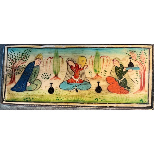 Antique Middle Eastern brass box featuring a hand-painted Persian miniature panel set into the lid. The scene depicts...