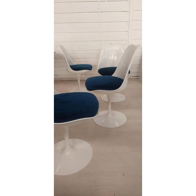 Four swivel "TULIP" chairs with white fiberglass shells on cast aluminum bases lacquered in white. Seats with removable...