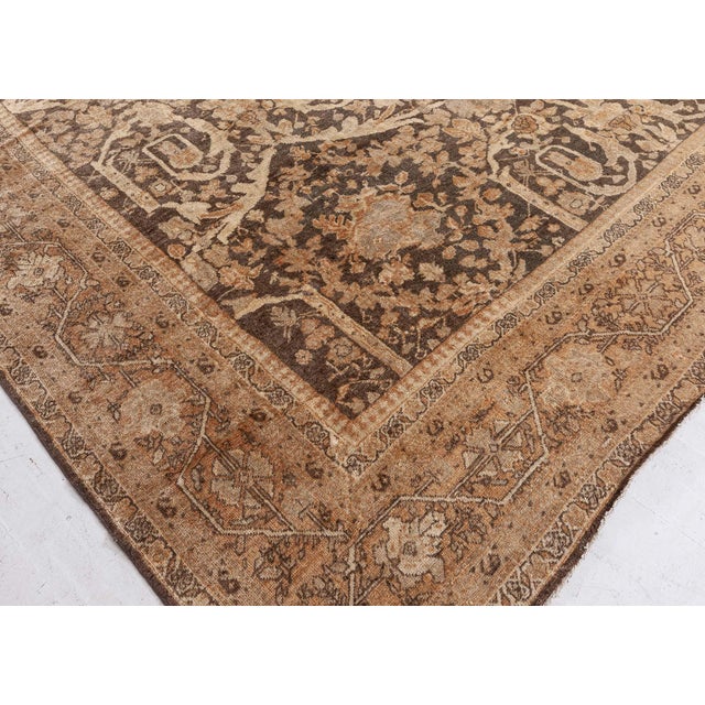 An early 20th century Persian Sultanabad rug, the abrashed brown field with an allover pattern of scrolling vines, split...