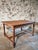 An antique French dining table from the early 20th century, crafted from oak and elm. This farmhouse-style table showcases...