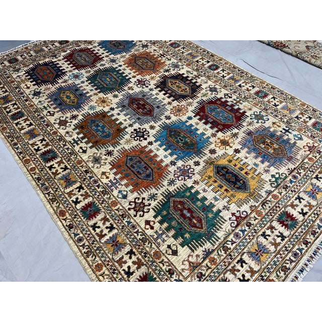 This Afghan Sultani natural dye wool area rug features an ivory field with fifteen geometric medallions arranged in three...