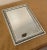 A raised ornate detail in silver finish with a light teal color underlay surrounds this wall mirror. The tone is soft...