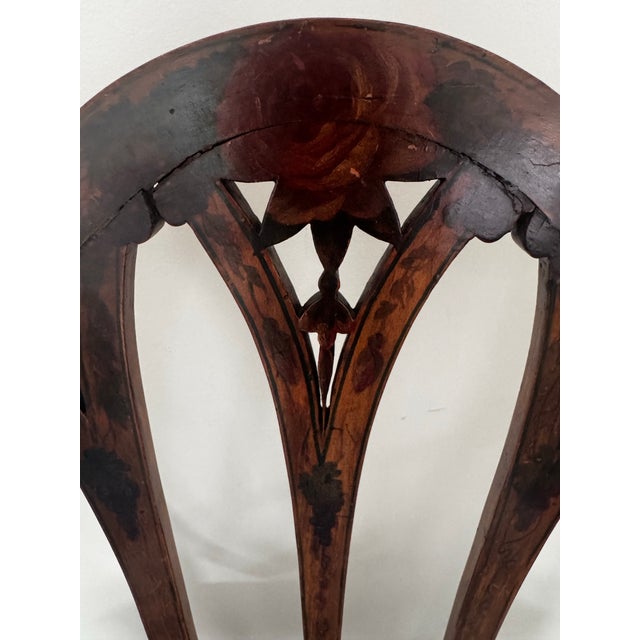 Elegant vintage shield-back armchair featuring a beautifully shaped wood frame with delicate decorative detailing and...