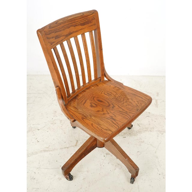 Antique swivel quarter sawn oak office chair made by Jasper Seating Company. It features a vertical back slatted design, a...