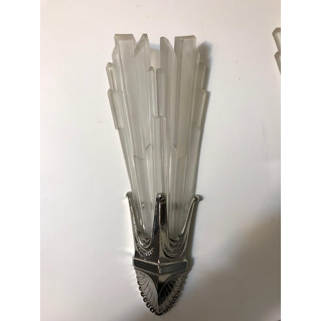 Pair of French Art Deco sconces by G Leleu. Having clear frosted glass shades with geometric motif details throughout....