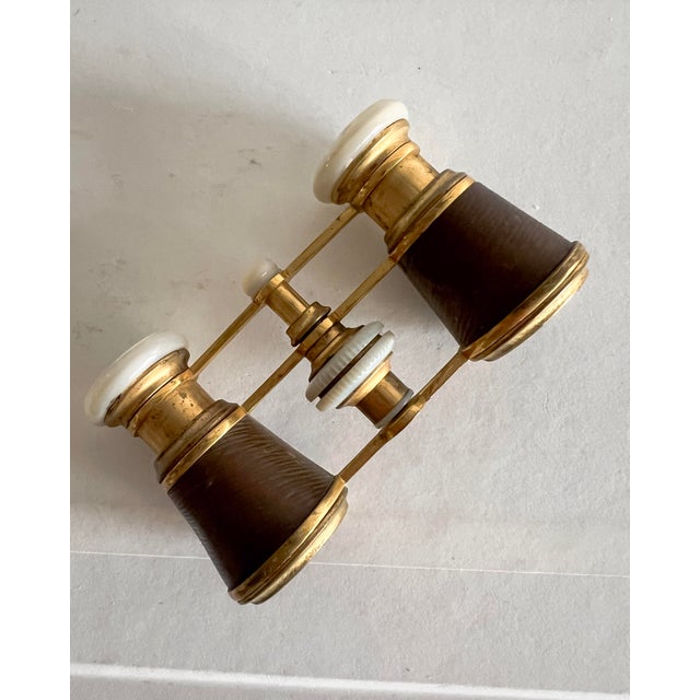 A refined pair of vintage French opera glasses attributed to Gualdoni, a Parisian optical maker, featuring warm brass...
