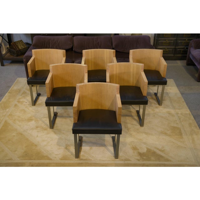 A set of six armchairs with an architectural design typical of the 1980s, combining light oak and black leather seats. The...