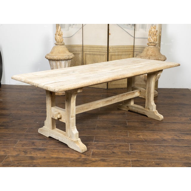 A rustic English natural wood farm table from the 19th century, with trestle base and weathered patina. Created in England...