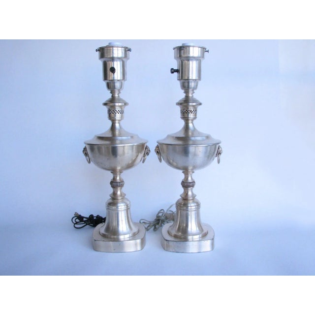 Antique pair of Colonial Premier Company table lamps. Classic urn shape, bearing lion's mask and ring handles. English...