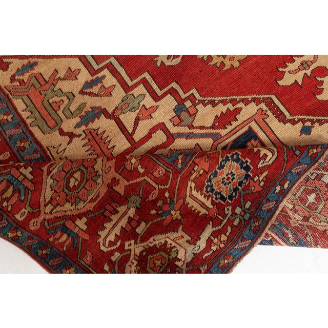 An early 20th century Persian Heriz antique rug displays enlarged central medallion decorated with vines and palmettes...