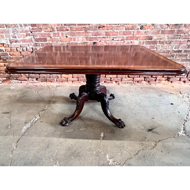 Antique English carved mahogany pedestal dining table with inlaid border and stunning claw feet. Tabletop: The rectangular...