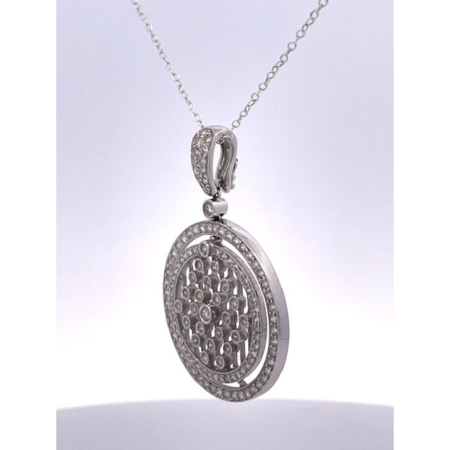 This elegant 18K white gold (750) diamond pendant necklace features a stunning circular medallion design with intricate...