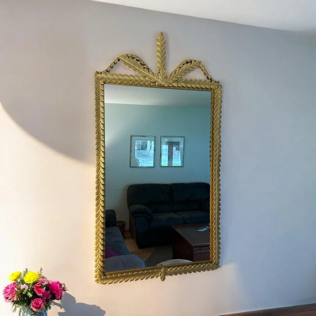 Offering a large vertical mirror with metal laurel leaves throughout. In the manner of Louis XVI Neoclassical Empire. A...