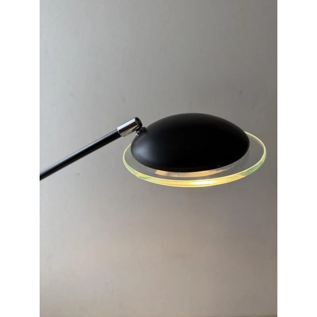 A slender floor lamp in which the construction forms an important part of the design. The long arm balances on the central...