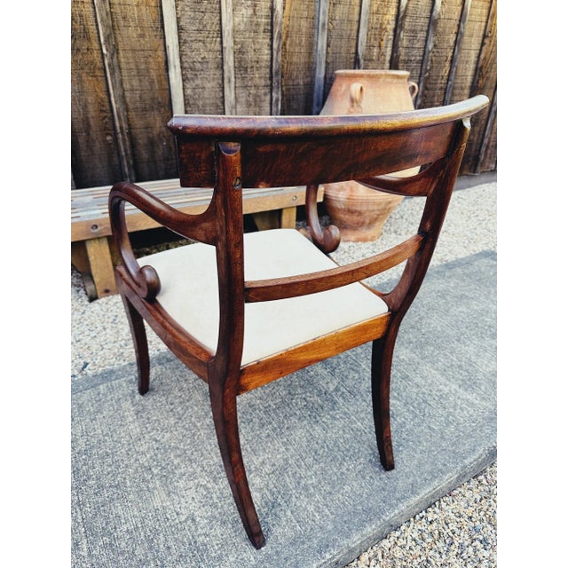 Solid mahogany armchair probably early to mid 19thC Regency period with slip seat and open scroll arms. Saber legs at...