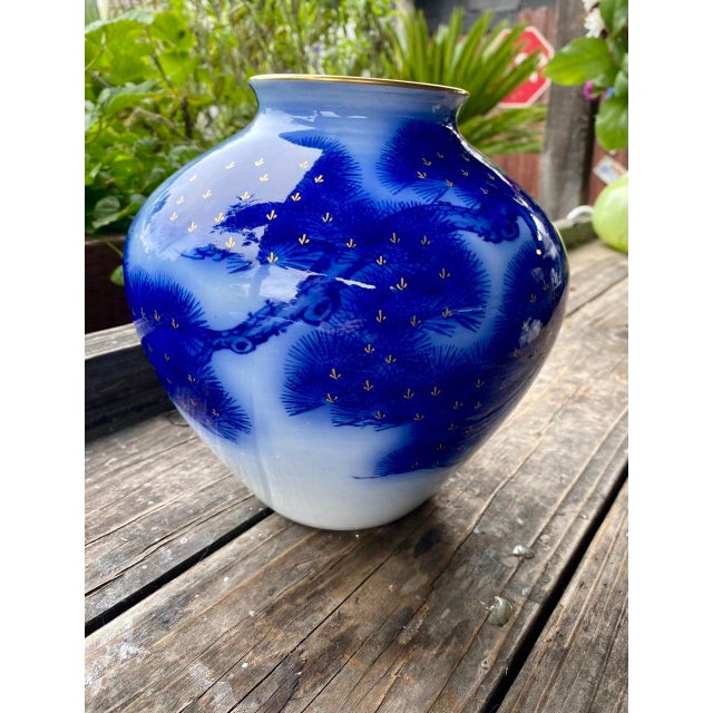 A beautifully executed vintage Japanese porcelain vase featuring flowing cobalt blue pine boughs against a snowy white...