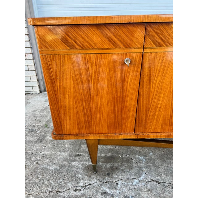 A striking French Mid-Century Modern sideboard crafted in rich mahogany, dating to the 1950s. Featuring beautifully...