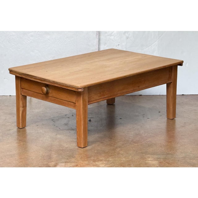 A large French cocktail or coffee (low) table of finely patinated pine wood, featuring a handsome rectangular plank top...